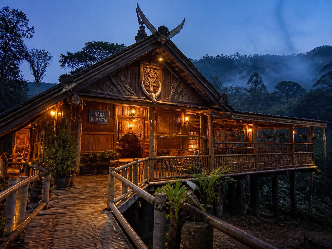 Traditional Naga wooden homestay lit at dusk